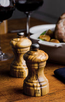 Moulin à poivre Peugeot en bois d'olivier sur table avec viande et vin rouge